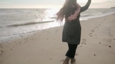 Kumlu deniz sahillerinde koşan mutlu etnik kadın ayakları. Neşeli, gülümseyen, rüzgarda uçuşan havadar kadın saçı. Pov, beni takip et. Yeşil ceketli, pembe atkılı bir kız resmi. Rüya gibi sinematik çekim..