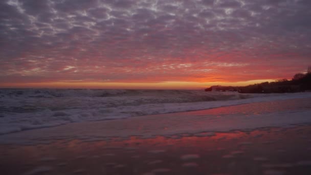 海浪冲刷着海滩上令人惊奇的梦幻般的落日 黄昏后 浅浅的海滩上的粉色和蓝色的天空 上面有紫色的云彩 潮落在防波堤上 日出时带着泡沫的码头 — 图库视频影像