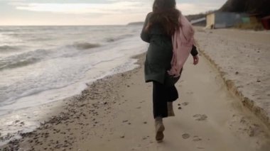 Kumlu deniz sahilinde kaçan oldukça karışık etnik bir kadın. Neşeli, gülümseyen Asyalı, havadar, rüzgarda savrulan bir kadın. Pov, beni takip et. Açık elli kız sahilde eğleniyor. Rüya gibi sinematik slomo..