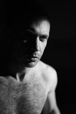 Sert kenar lambası altında meditasyon yapan yakışıklı bir adamın portresi. Erkek yüzünün yarısı güneşin doğuşuyla aydınlanır. Kişisel yansıma ve depresyon kavramı. Meditasyon ve ruhani dua için huzur verici bir yer..