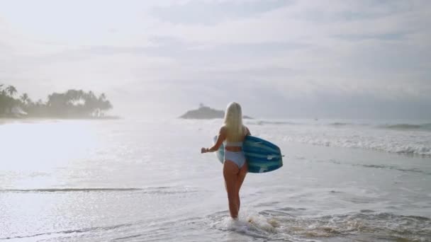 Young Blonde Woman Surfer Bikini Holding Surfboard Walking Ocean Tropical — Vídeo de Stock
