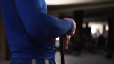 Athletic man wrapping hands with boxing bandages at gym. Male fighter wrapping his hands with black protection bandages. Male athlete preparing for fight in gym. Sport, active lifestyle concept. 