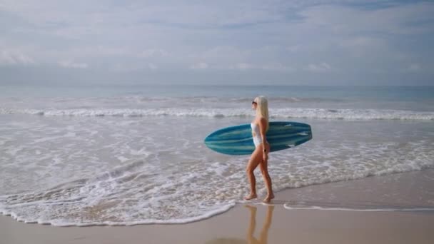 Mujer Rubia Joven Surfista Bikini Sosteniendo Tabla Surf Caminando Hacia — Vídeo de stock