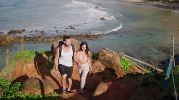 Biracial Tourist Couple Backpacks Walking Scenic Rocky Hill Covered Greenery — Vídeo de Stock