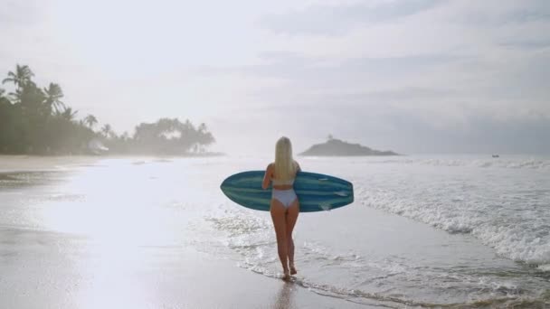 Mujer Rubia Joven Surfista Bikini Sosteniendo Tabla Surf Caminando Hacia — Vídeo de stock