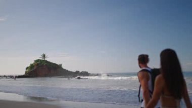Young biracial happy couple holds hands and walking on beach enjoying summer unfocused closeup. Cheerful boyfriend and girlfriend relaxing and walking at seaside at sunrise portrait blurred.