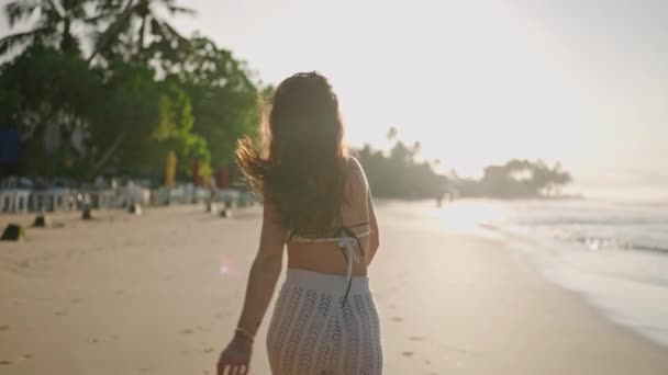 若い陽気なラテン語の女性が逃げるカメラに背を向ける彼女の手を海に彼女のボーイフレンドを招待伸ばす カメラから走っている幸せな本物の女の子は 熱帯のエキゾチックなビーチを海に引き返します Pov — ストック動画