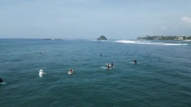 12 Ocak 2023 - Midigama, Sri Lanka. Sörf tahtalarındaki sörfçülerin üst hava görüntüsü Hint Okyanusu 'ndaki sörf yerinde mükemmel bir dalga bekliyor. Sörfçüler denizde sörf tahtalarında oturuyor.
