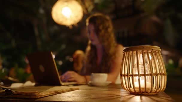 女自由职业者晚上在室外的热带地区工作 女人们坐在外面的黑暗咖啡馆里 用暖灯 稻草灯和木灯 用笔记本电脑 加班时间 — 图库视频影像