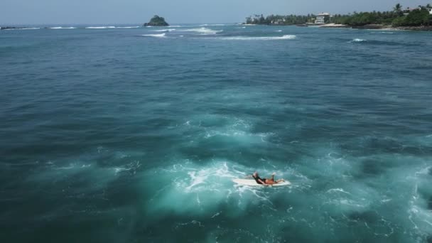 若い女性サーファーはスリランカの空撮で小さな暗い緑色の破壊波を彫刻します プロのサーファーの女の子はドローンからの波の景色に乗っています 陽気観光シーズンの彼女の最初の波に乗る — ストック動画