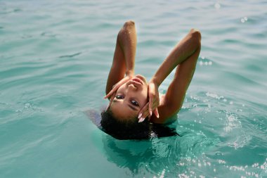 Portrait of serene looking attractive young black female posing in bikini in water. African model posing in sea. Multiracial woman posing at the beach in ocean. Fashion portrait of black woman