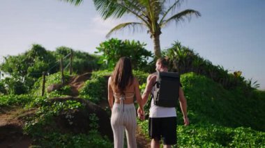 Çift ırklı turist çifti, tropikal nefes kesici manzarada egzotik bitkiler ve yeşilliklerle kaplı kayalık tepelere tırmanıyor. Resimde gezinen genç yetişkinler kaya arka plan çekimleri