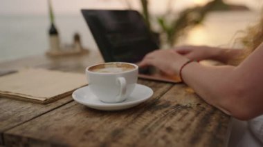 Dizüstü bilgisayarda çalışan genç bir bayan müteahhit okyanus kenarında uygulamalar yaratıyor. Açık hava tropikal kafede serbest çalışan bir kadın. Kafkas kız egzotik bir yerde uzaktan çalışıyor. Dünya çapında iş kavramı