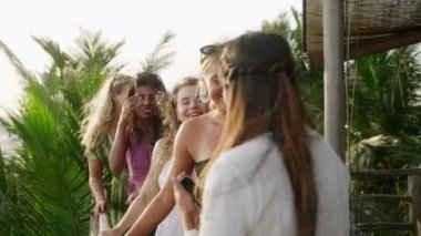 Neşeli çok ırklı kızlar tatilde selfie çeker. Çeşitli genç dişiler akıllı telefonla kendi portresini çekiyor. Çok ırklı mutlu kadın arkadaşlar gülümsüyor ve egzotik yerlerde gülüyorlar..