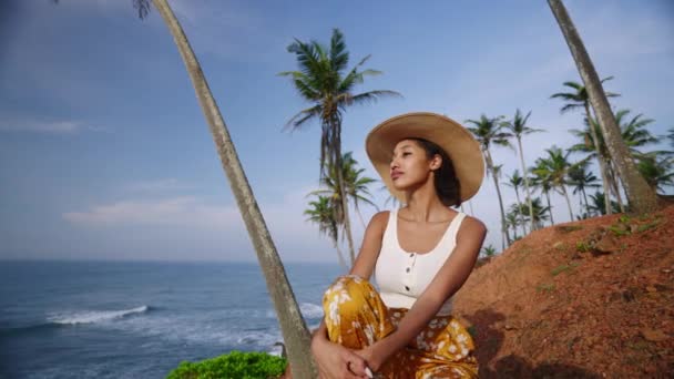 日出时分 年轻的非洲女模特穿着五彩缤纷的衣服 在美丽的热带地区 在大海中间的棕榈树之间晒太阳 黑人多民族女人悠闲地坐在异国情调的景色下欣赏大海 — 图库视频影像