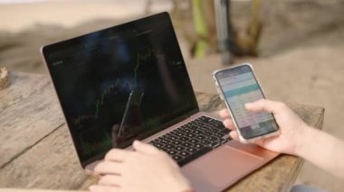 Akıllı telefondan istatistik çizelgelerini kontrol eden bilgisayardaki kadın kripto tüccarı. Şifreli para birimiyle uzaktan çalışan bir kadın telefonda şema kontrol ediyor. Şifreleme grafiklerini yakından inceleyen kadın analist