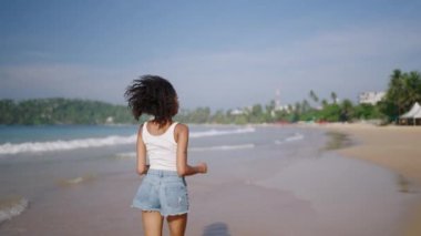 Çok ırklı siyahi kadın, okyanus sahillerinde egzotik adalarda tropik tatillerde koşuyor. Afrika kökenli Amerikalı kadın dönüyor, şapkasıyla deniz kıyısında koşuyor. Bipoc seyahat turunda eğleniyor. Beni takip et.