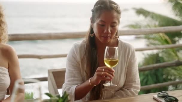 优雅的亚洲女人在海景餐厅品尝白葡萄酒 年轻的少数民族妇女在海滨的屋顶咖啡馆里闻到并喝着美味的酒精饮料 生活方式 — 图库视频影像