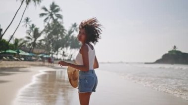 Çok ırklı siyahi kadın, okyanus sahillerinde egzotik adalarda tropik tatillerde koşuyor. Afrika kökenli Amerikalı kadın dönüyor, şapkasıyla deniz kıyısında koşuyor. Bipoc seyahat turunda eğleniyor. Beni takip et.