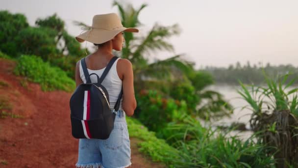 美しいアフリカの女性は日の出に島に立つ海の景色を楽しんでいます エキゾチックな海の目的地への旅行にわら帽子の観光で出産の女性 観光Bipoc思慮深い女の子熟考し リラックス — ストック動画