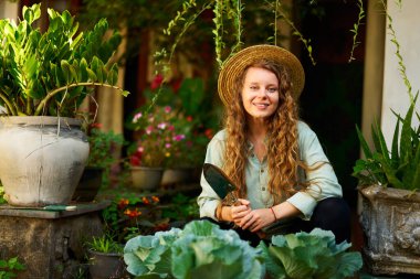 Bahçede hasat şapkalı mutlu çiftçi kadın sebze hasadıyla ilgileniyor. Bahçesine lahana dikerek gülümseyen genç bir kadın kameraya bakıyor. Çiftçilik ve bahçecilik kavramı