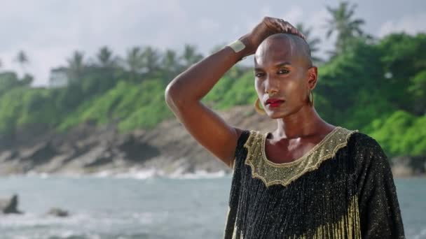 Flamboyante Zwarte Man Een Luxe Jurk Poseert Een Schilderachtig Oceaanstrand — Stockvideo