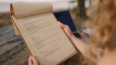 Kadın parmağı restoran menüsünü işaret ediyor. Tanımlanamayan bir kadın menüden öğle ya da akşam yemeği için yemek seçer. Genç bir bayan açık kafede menü okuyarak yiyecek ve içecek topluyor.