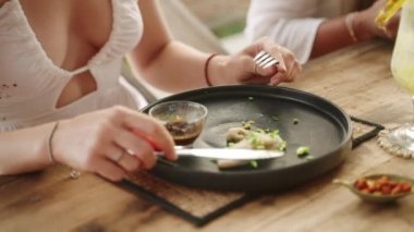 Restoranda çatal ve bıçakla gyoza yiyen bir kadın. Genç bir bayan arkadaşlarıyla kafede geleneksel Çin mantısı yiyor. Doğu mutfağından hoşlanan genç bir kız..