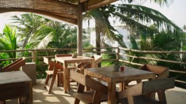 Otelde müşterileri ve müşterileri bekleyen deniz kenarındaki boş tropikal çatı restoranı. Egzotik bir yerde, ahşap sandalyeleri ve masaları olan otantik bir kafe. Güneşli bir günde kimse olmaz. Yaz tatili kavramı