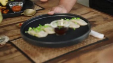 Tablada bronzlaşmış kadına yemek servisi yapan garson. Garson tabağı bir tepsiden nefis yiyeceklerle alıyor ve masaya yakın bir yere koyuyor. Kadın müşteriler için restoran masasına el yapımı gurme yemeği..