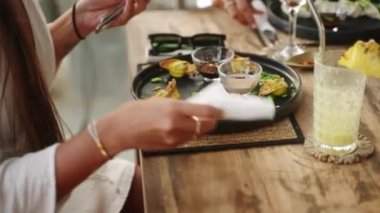 Çatal ve bıçak tutan kadın elleri siyah tabakta servis edilen soya soslu wonton yemeye hazır. Lokantada servis edilen karanlık sofra takımında servis edilen doğu mutfağı tabağı. Akşam yemeği için geleneksel Asya yemekleri.