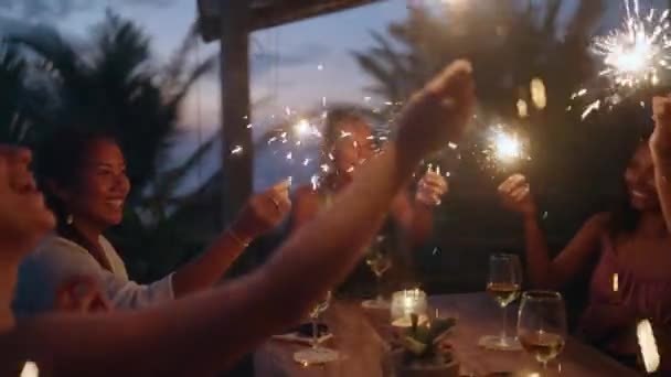 パーティーで燃える輝きを保持し 手を振る多様な女性 お祝いの夕食中に輝くライトを手に楽しい多人種の若い女性 誕生日だ クリスマス — ストック動画