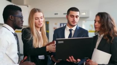 Businessman shows data for briefing on laptop. International business partners discuss project results on meeting in an office. Multiethnic corporate team planning. People brainstorming on briefing.