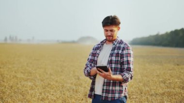 Hassas, akıllı çiftçilik. Çiftçi buğday tarlasında online veri yönetim yazılımı kullanarak tablet tutuyor. Dokunmatik bilgisayar, kontrol ve tarım işleriyle uğraşan bir tarımcı. Yenilikçi teknoloji.