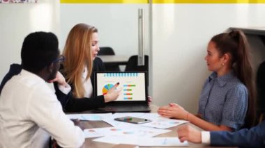 Business woman makes a presentation with charts, diagrams for multiethnic partners. Startup team discuss project plan. Diverse multinational people have meeting in office listening to a supervisor.