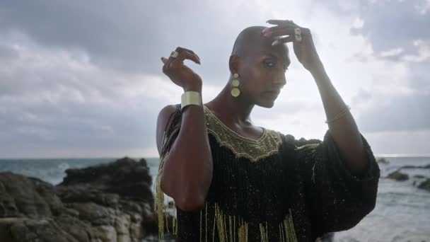 Queer Μαύρο Άτομο Πολυτελές Φόρεμα Χειροποίητα Κοσμήματα Ποζάρουν Βραχώδη Παραλία — Αρχείο Βίντεο