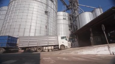 Tahıl kamyonu tahıl asansörü terminaline geliyor. Çöp kamyonu boşaltıcıya gidiyor. Kargo gövdesinde buğday. Tahıl sevkiyatı ve tarım ürünlerinin nakliyesi. Dünya gıda tedarik zinciri.