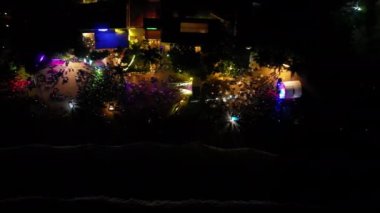 Bir sıra deniz kenarı gece kulübü havadan deniz manzaralı. Deniz kenarındaki kafeler ve restoranlar geceleri renkli ışıklar, Noel kutlamalarında deniz kenarındaki diskoda kalabalık dans ediyor.