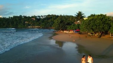 Tropik kumlu plajda genç bir çift şafak vakti deniz kenarında el ele yürür. Erkek arkadaş ve kız arkadaş yürür, gün doğumunda deniz kenarında suyun yanında havadan konuşurlar.