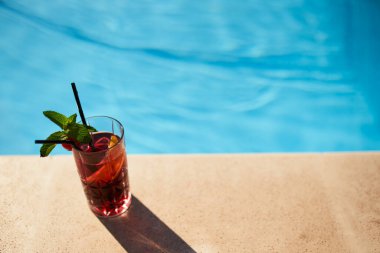 Yüzme havuzu güvertesinde naneli ve kirazlı çilekli kokteyl. Su arka planında fotokopi alanı olan alkollü içecek tazeleniyor. Tatil beldesi ve spa konsepti.