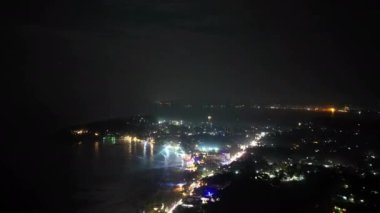 Deniz kıyısındaki gece kulübünün hava manzarası hipervane. Deniz kenarındaki kafe ve restoranlar gece renkli ışıklarla parıldıyor, Noel kutlamaları sırasında kalabalık deniz kenarındaki diskoda dans ediyor.