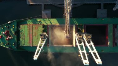 Yukarıdaki hava manzarası - buğday deniz limanındaki deniz tahıl asansöründe yük ambarına yükleniyor. Buğday sevkiyatı ambardan gemiye deniz limanı terminalindeki sandıkla taşınıyor. Deniz taşımacılığı.