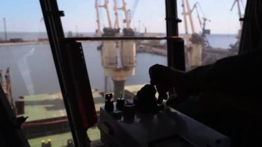İnsan elleri buğday terminalinin iş yerinde joystickleri kontrol eder. İşçi, yükleme kolu ile tahıl yükleme kontrol silo 'dan bölme gemi hareket halindeki bir rıhtım makinası aracılığıyla.