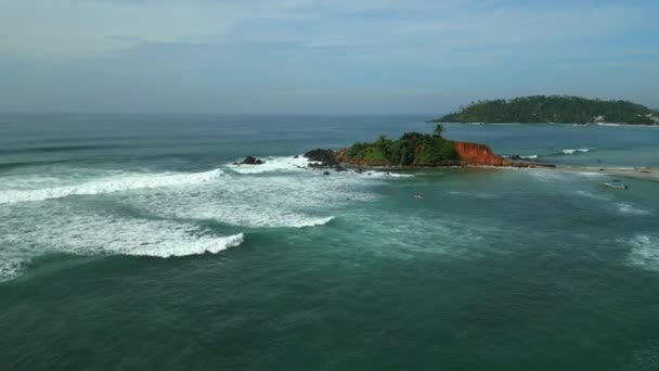 热带岩石岛屿在大海中被海浪冲刷着 斯里兰卡米里萨市著名的具有里程碑意义的Coconut Hill被无人机拍到的海浪冲刷过 海滨度假胜地城镇在海滨俯瞰 — 图库视频影像