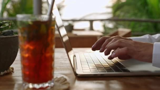 カフェでラップトップのキーボードを入力する女性 作家は詩を作っている アイスティー ヤシの木で屋外のコワーキングでノートを使用して電子メールを作成する人 ジャーナリストの記事 ブロガーの投稿 — ストック動画