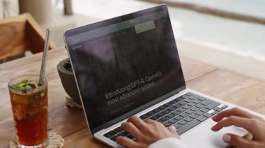2023-04-24, Midigama, Sri Lanka. Morena Oteli. Bilgisayarda Google 'da arama yapan bir kadın ChatGPT sohbet robotuyla OpenAI sitesine giriyor. Buzlu çayla birlikte çalışan kişi, internette google web araması yapar.