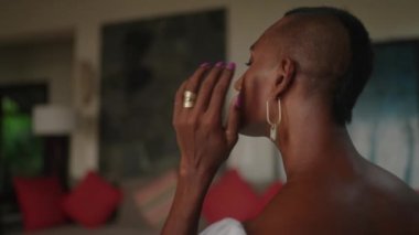 Androgynous siyah gelini düğün töreni için altın renkli küpeler takıyor. Beyaz giysili nazik eşcinsel adamın yakın plan fotoğrafı. Zarif cinsiyet akışkan gelin elleri ve düzgün bir manikür..