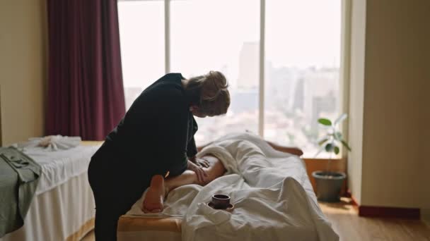 Mulher Massagista Faz Massagem Óleo Perna Para Jovem Bronzeado Cliente — Vídeo de Stock