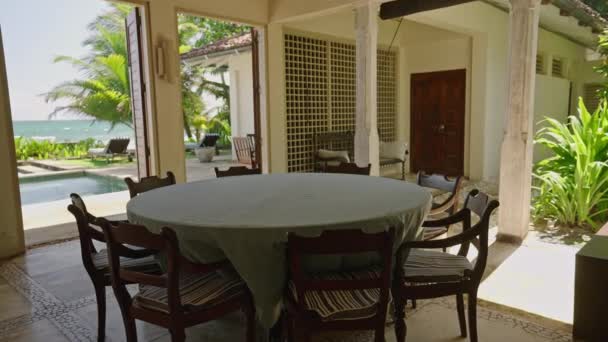 热带岛屿上的豪华复古别墅中 有蓝色海洋和棕榈树景观的圆形餐桌 热带古屋的游泳池 为八人提供早餐的地方 — 图库视频影像