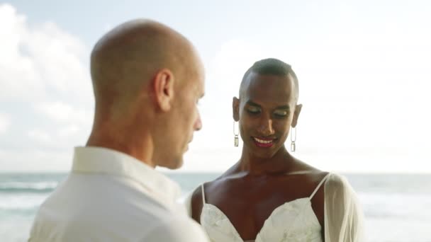 アンドロギーナス黒人 婚約後に海岸で愛情を持って見ている彼の婚約者 ゲイ多民族カップルは 結婚式のドレスでリングに置かれ スーツは熱帯の島でハネムーンを楽しんでいます — ストック動画